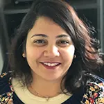 Anu V., Director of Technology, smiling in a floral-patterned blouse with a warm and inviting expression.