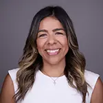 Thalia V., Business Development Associate, smiling in a professional headshot with a neutral gray background.